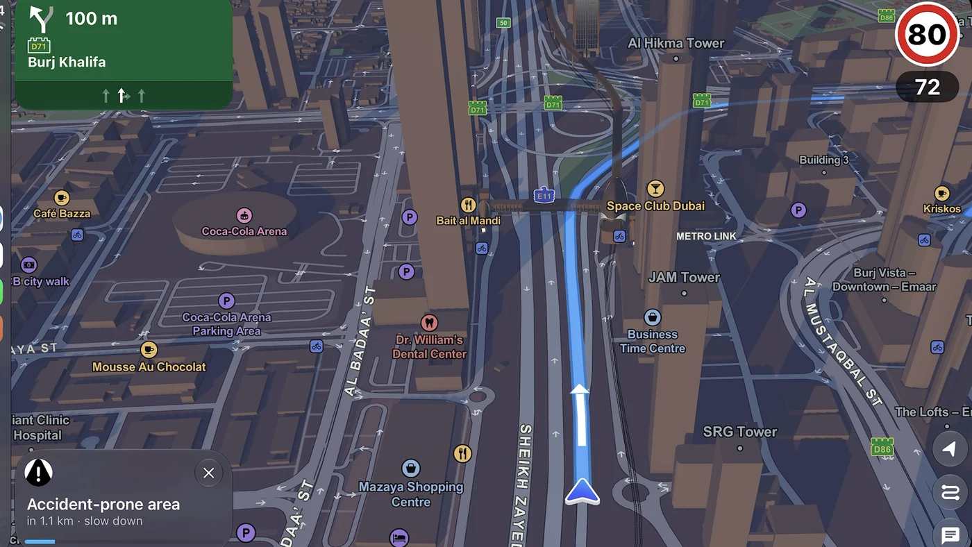 Guardian AI on CarPlay in a car dashboard: 3D Sheikh Zayed Road, green sign for Burj Khalifa in 100 m and a card, accident-prone area in 1.1 km, slow down